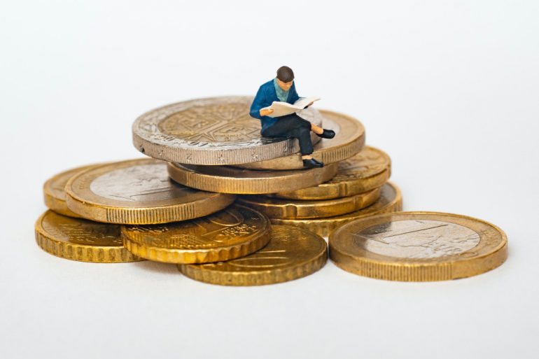 man sitting on giant coins