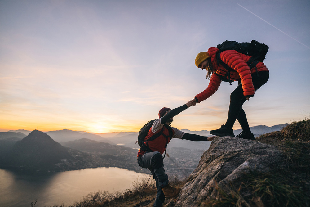 partner giving a hand to climb mountain